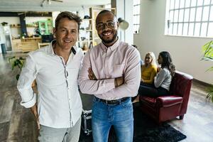 Portrait of two smiling businessmen with coworkers in background in loft office photo