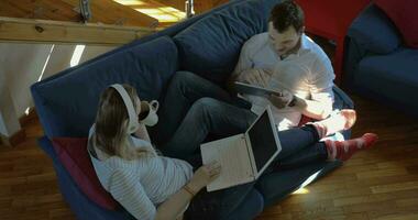 Man and woman at home using pad and laptop video