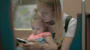 maman en utilisant téléphone portable pendant métro balade avec peu fille video