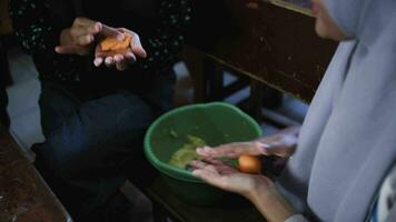 Video footage of two Indonesian Muslim women working together to make cake dough in the kitchen.