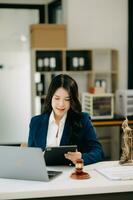 Beautiful asian woman lawyer working and gavel, tablet, laptop in front, Advice justice and law concept. photo