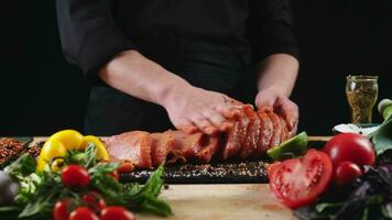 chef toepassen korrelig zout Aan rauw stuk van steak. kookplaat voorbereidingen treffen vlees Aan professioneel keuken tafel met divers groenten 4k beeldmateriaal video