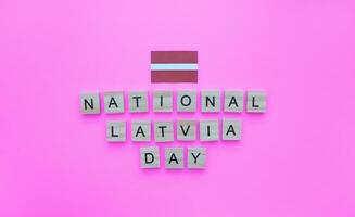 noviembre 18, independencia día de letonia, el bandera de letonia, un minimalista bandera con un inscripción en de madera letras en un rosado antecedentes foto