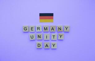 October 3, German Unity Day, the flag of Germany, a minimalistic banner with the inscription in wooden letters on a blue background photo