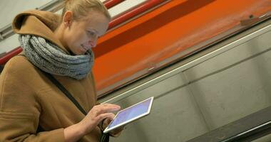 Woman on escalator using tablet computer video