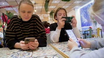 mam en kinderen zijn Aan hun telefoons in een cafe - 1 video