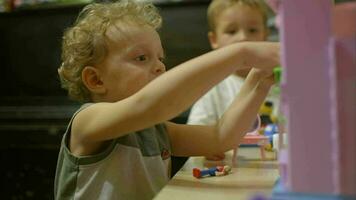 liten Pojkar spelar med leksak hus på Hem video