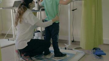 At the medical clinic Evexia on a robotic system analysis and training balance doctor trains a little boy to keep the balance video