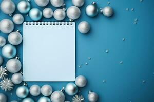 Christmas blue background with blank paper and blue metallic decorations on a table. Top view photo