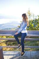 the girl sits on a bench on the mountain in Pilipets and looks at the fog photo