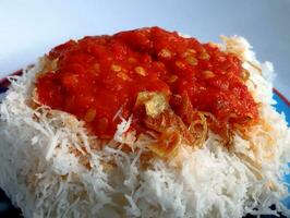 Indonesian food, sticky rice topped with grated coconut and red chili sauce photo