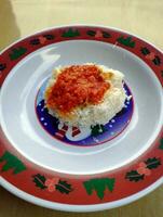 Indonesian food, sticky rice topped with grated coconut and red chili sauce photo