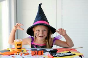 A little girl in a witch costume looks at the camera and scares. photo