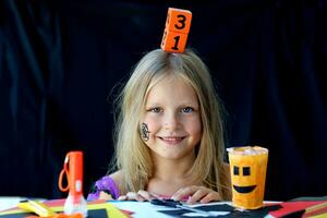 A little girl holds on her head a wooden calendar with the date of October 31. photo