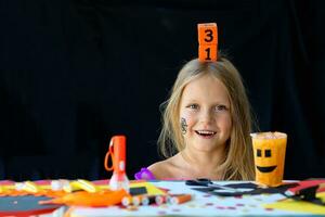 A little girl holds on her head a wooden calendar with the date of October 31. photo