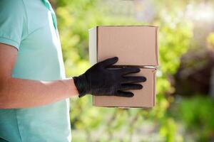 Delivery man holding cardboard boxes in medical rubber gloves on blurred background. Fast and free Delivery transport . Online shopping and Express delivery . photo