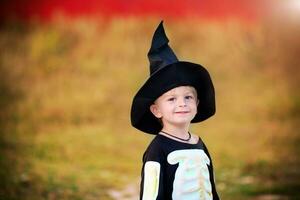Portrait of a little boy wearing a skeleton costume and a black hat. Halloween holiday. photo