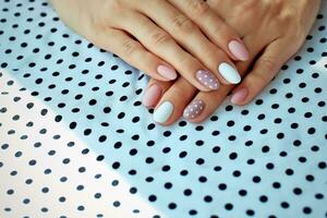 Female hands with a beautiful manicure, on polka dots background. Autumn trend,  polish beige and white polka dots on nails with gel polish, shellac. photo