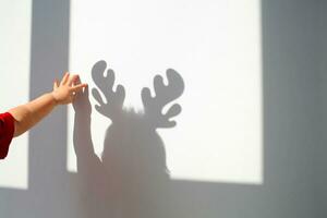 niño toques su sombra en el pared con su mano. sombra de un niño con ciervo cornamenta, Navidad concepto. foto