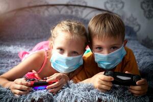 Playful children play computer games with a joystick in a mask. photo