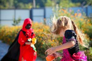 un niña vestido como un bruja carreras lejos desde un chico vestido como un verdugo. foto
