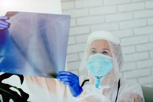 el médico en son vistiendo ppe mira a el radiografía fotografía. foto