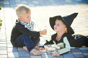 A kid in a skeleton costume feeds a child with sweets , halloween. photo