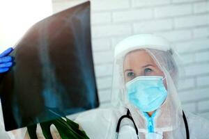The doctor in PPE looks thoughtfully at the X-ray. photo
