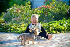 Little boy sits in a skeleton suit next to a dog. Halloween holiday. photo