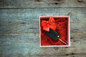 coche llave en un regalo caja con un rojo cinta arco en un de madera antecedentes. regalo para Navidad o enamorado es día o presente un resumen concepto. foto