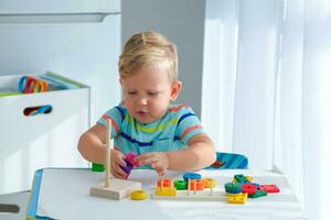 pequeño chico 2 años antiguo es jugado con un colores juguetes educativo lógica juguetes para niños. montessori juegos para niño desarrollo. foto