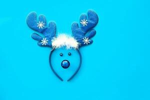 Christmas reindeer concept made from hoop with deer antlers, red decoration toy on blue background.  Flat lay top view . photo