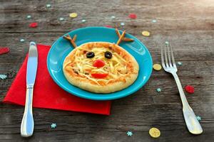 Christmas pizza in a shape of reindeer and cutlery  on a wooden background. photo