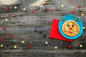 Christmas pizza in a shape of reindeer on a wooden background. Copy space. photo