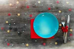 Christmas dinner background, empty blue plate, fork, knife and festive decoration on wooden table, top view. photo