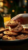 Close up Womans hand reaches for chocolate cookies, balancing them with orange juice Vertical Mobile Wallpaper AI Generated photo