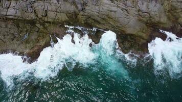 Aerial view of sea waves crashing on rocks cliff in the blue ocean. Top view of coastal rocks in Phuket ocean. Landscape view point of Laem Phromthep Cape in the morning. video