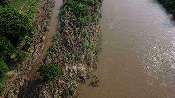 aéreo Visão do turvo Castanho floresta água fluindo dentro uma rio durante a chuvoso estação dentro norte tailândia. Visualizações do Chiang mai aldeias e a ping rio a partir de uma drone. video