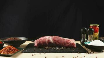The chef cuts raw meat with a knife in slow motion. Raw beef steak sliced on a wooden board with spices and herbs. Delicious food concept video
