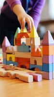 A child's hands building a simple house with colorful plastic blocks photo