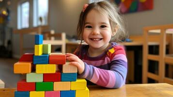 un pequeño niña sonriente mientras creando un arco iris torre con bloques foto