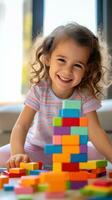 un pequeño niña sonriente mientras creando un arco iris torre con bloques foto