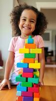 A little girl smiling while creating a rainbow tower with blocks photo