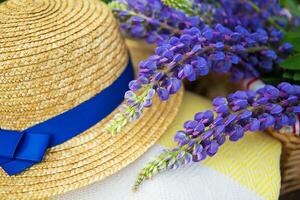A hat, a plaid and a bouquet of lupines in a basket, close-up photo