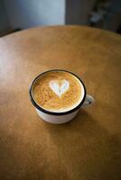 taza de capuchino con un corazón conformado modelo en un de madera mesa foto