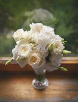 hermosas rosas blancas en un jarrón de cristal cerca de la ventana. foto