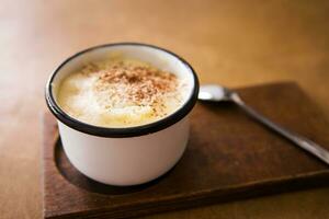 a cup of cappuccino stands on a wooden table and stands for a spoon photo