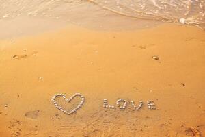 On the sand shells lined with heart and the word love photo