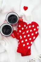 romántico todavía vida, dos rojo tazas de café en un blanco tartán juntos con rojo mitones. San Valentín día concepto, tarjeta listo. foto