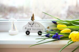 beautiful flowers-tulips and irises lie on the windowsill with a typewriter and a Christmas tree photo